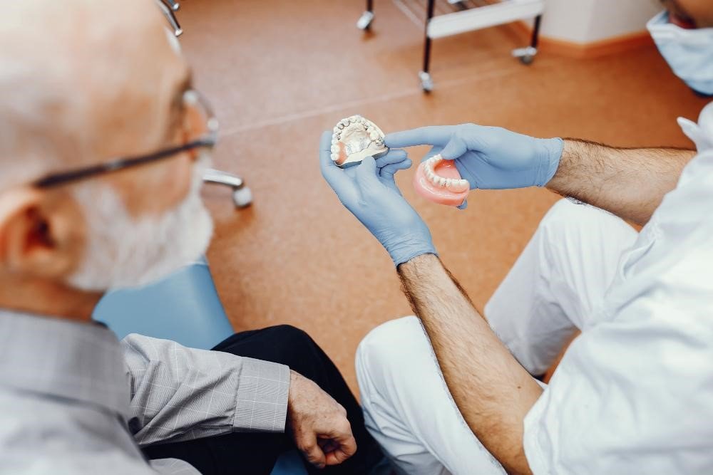 expert explaining dentures vs implants benefits to patient